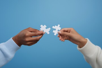 Diverse hands connecting puzzle pieces on blue background