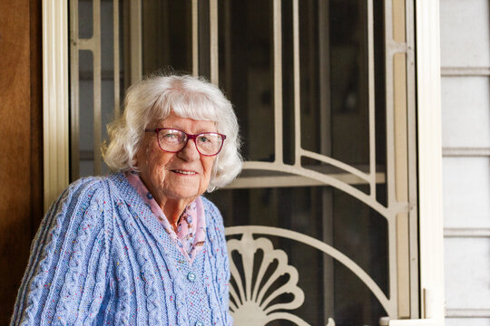 Portrait of 99 year old elderly Australian woman standing by front door of her home