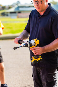 man giving tool demonstration standing outside showing grip on drill