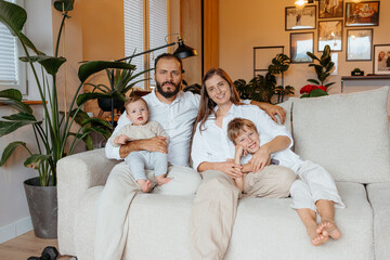 Happy family with two children relaxing on sofa