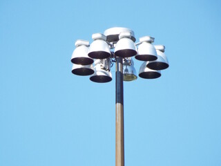 Create 20 comma separated keyword tags for this text :
A close-up of a tall metal light pole topped with a cluster of several high-intensity floodlights 
