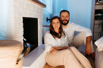 Happy family couple relaxing at home near fireplace