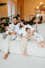 Happy young family relaxing together on couch at home