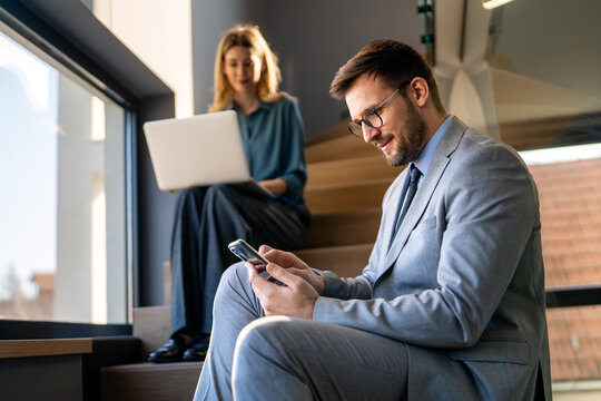 A confident business man leads her busy office life, multitasking with smartphone communication