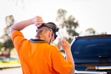 trade apprentice putting on face shield protective safety equipment to use angle grinder tool