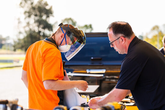 instructor helping student put on PPE apron and face shield before using tool during demonstration