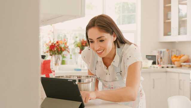 Woman At Home in Kitchen Following Recipe On Digital Tablet