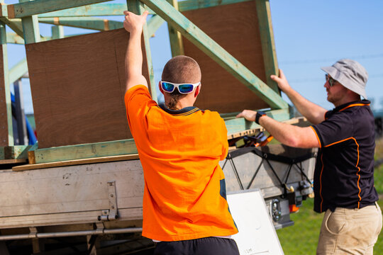 trade teacher and apprentice lifting wooden workbench onto ute together