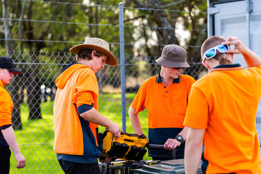 trade apprentices working together to pack up tools at worksite during hands on learning course