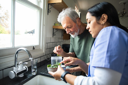 Senior man cooking with caregiver in kitchen