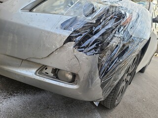 Destroyed car in car crash traffic accident on city road on city road. Smashed broken front auto headlight, dented hood without bumper in car accident. Auto life and health insurance. square