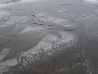Closeup pieces of cracked ice over body of water or river frozen in cold weather after winter frosts.