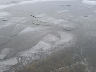 Closeup pieces of cracked ice over body of water or river frozen in cold weather after winter frosts.