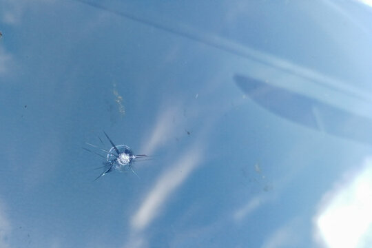 A close-up of a chip from a stone impact on a car windshield