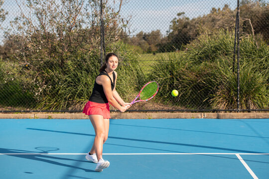 young woman playing tennis on a blue outdoor court