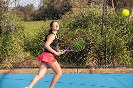 young woman playing tennis on a blue outdoor court