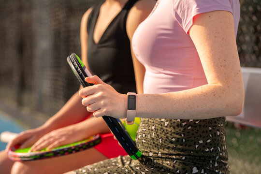 female tennis player with wearable fitness tracker and tennis racquet