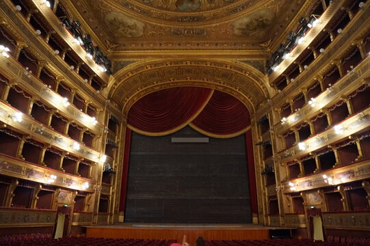 The grand auditorium and stage of the historic Teatro Massimo opera house in Palermo, Sicily, showing the ornate golden boxes and red velvet curtain