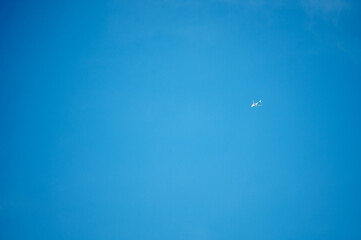 A distant airplane captured in the middle of a clear blue sky.