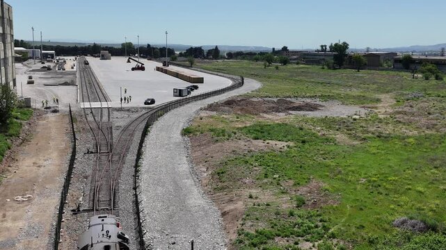 Aerial 4K drone footage of reach stackers handling shipping containers at a modern container terminal. Industrial port operations, cargo loading and unloading, logistics and transportation process in 