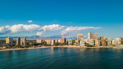 Fototapeta premium Aerial panoramic view of Alicante coastline in Spain with modern apartment buildings, sandy beaches, and turquoise Mediterranean water under a clear summer sky