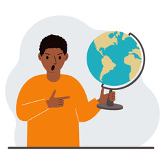 A man holds a globe in his hand and points his finger at it. The concept of education, teacher, world conquest, ecology.