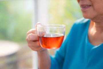 Close up senior asian woman enjoying drinking tea sitting on sofa with satisfied in living room at home, happy elder woman drinking tea or beverage for health and relaxation, lifestyle and health.