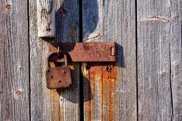 old vintage hasp and padlock close up on weathered wooden door with vertical boards,  suitable as background or banner  copy space room for text