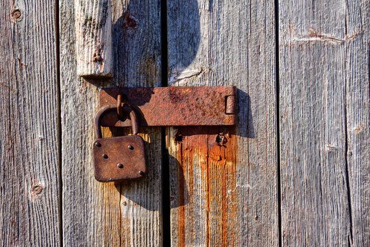 old vintage hasp and padlock close up on weathered wooden door with vertical boards,  suitable as background or banner  copy space room for text