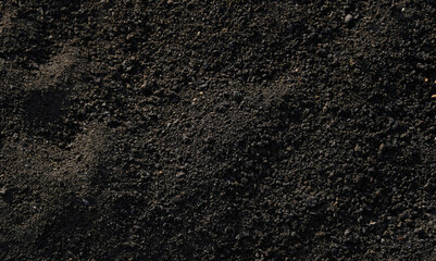 Rich, dark background texture of fine volcanic ash and pulverized lava gravel, ideal for geology, gardening, soil, and abstract natural themes.