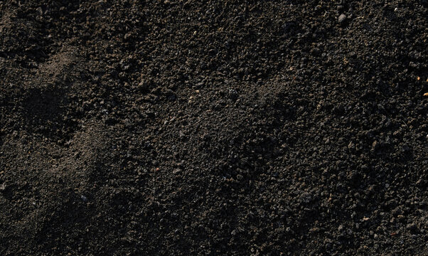Rich, dark background texture of fine volcanic ash and pulverized lava gravel, ideal for geology, gardening, soil, and abstract natural themes.