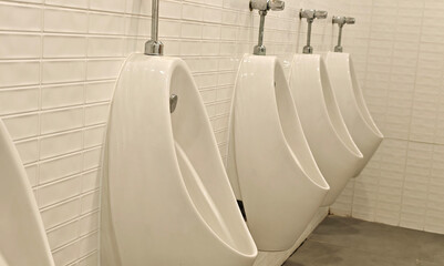 Men's public restroom, row of urinals, white urinals in the men's restroom