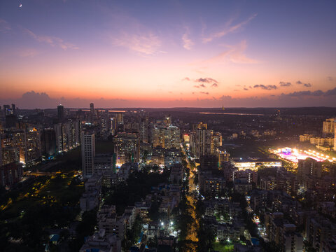 Aerial view of the city's vibrant skyline bathed in the soft glow of twilight, with the Arabian Sea in the distance, Mumbai, Maharashtra, India.
