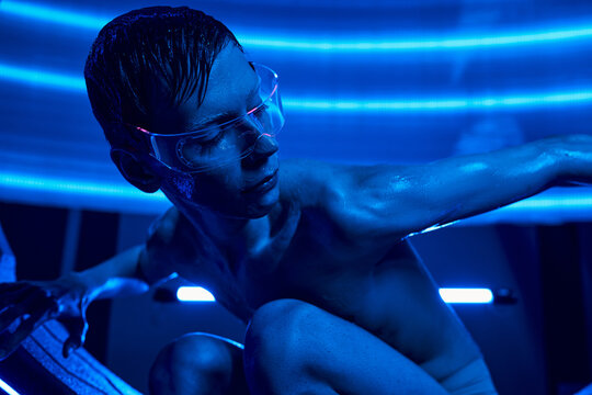 Tall alien interacts with advanced technology in a futuristic science lab environment