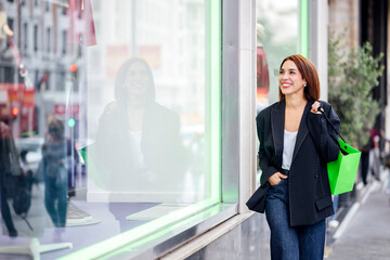 Fototapeta premium Woman holding shopping bag walking past store window