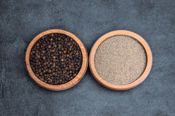 Black peppercorns  and ground black pepper powder on black background
