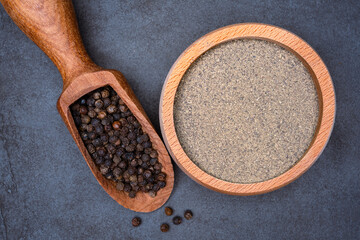 Black peppercorns  and ground black pepper powder on black background