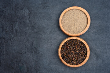 Black peppercorns  and ground black pepper powder on black background