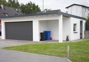 Modern suburban home garage and carport with trash cans