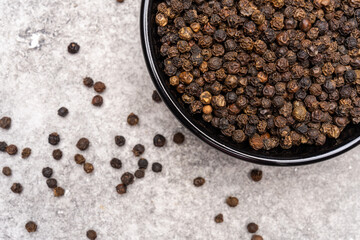 Black peppercorns on white stone table  background
