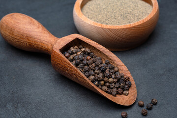 Black peppercorns  and ground black pepper powder on black background
