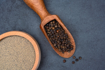 Black peppercorns  and ground black pepper powder on black background