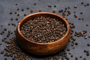 Black peppercorns on black stone table  background