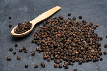 Black peppercorns on black stone table  background