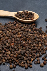 Black peppercorns on black stone table  background