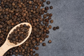 Black peppercorns on black stone table  background