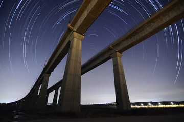 Parallel Railway Bridges at Night with Star Trails Around Polaris