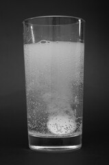 Tablet dissolving in a glass of water on black background