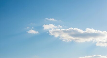 Fototapeta premium Sunlit, fluffy clouds drift serenely across a vast, clear blue sky backdrop