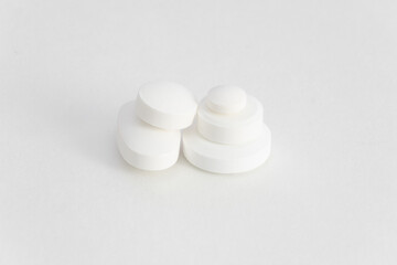 A small pile of various white tablets on a light background